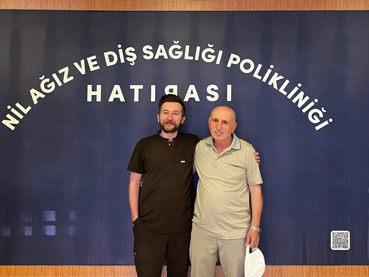 Porselen kron ve protez tedavisi tamamlanan hastamız, hekimiyle birlikte kliniğimizin hatıra panosu önünde
