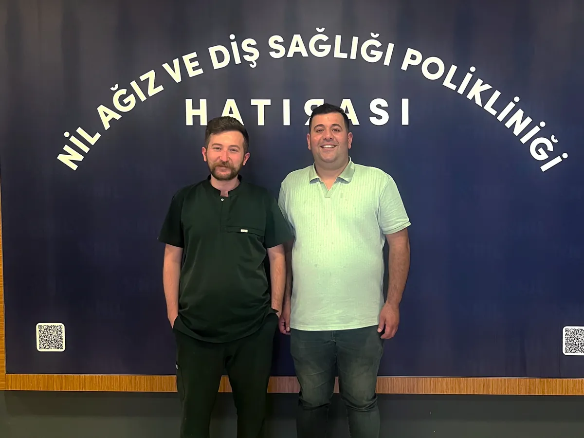 İmplant ve zirkonyum kron tedavisi tamamlanan hastamız, hekimiyle birlikte kliniğimizin hatıra panosu önünde